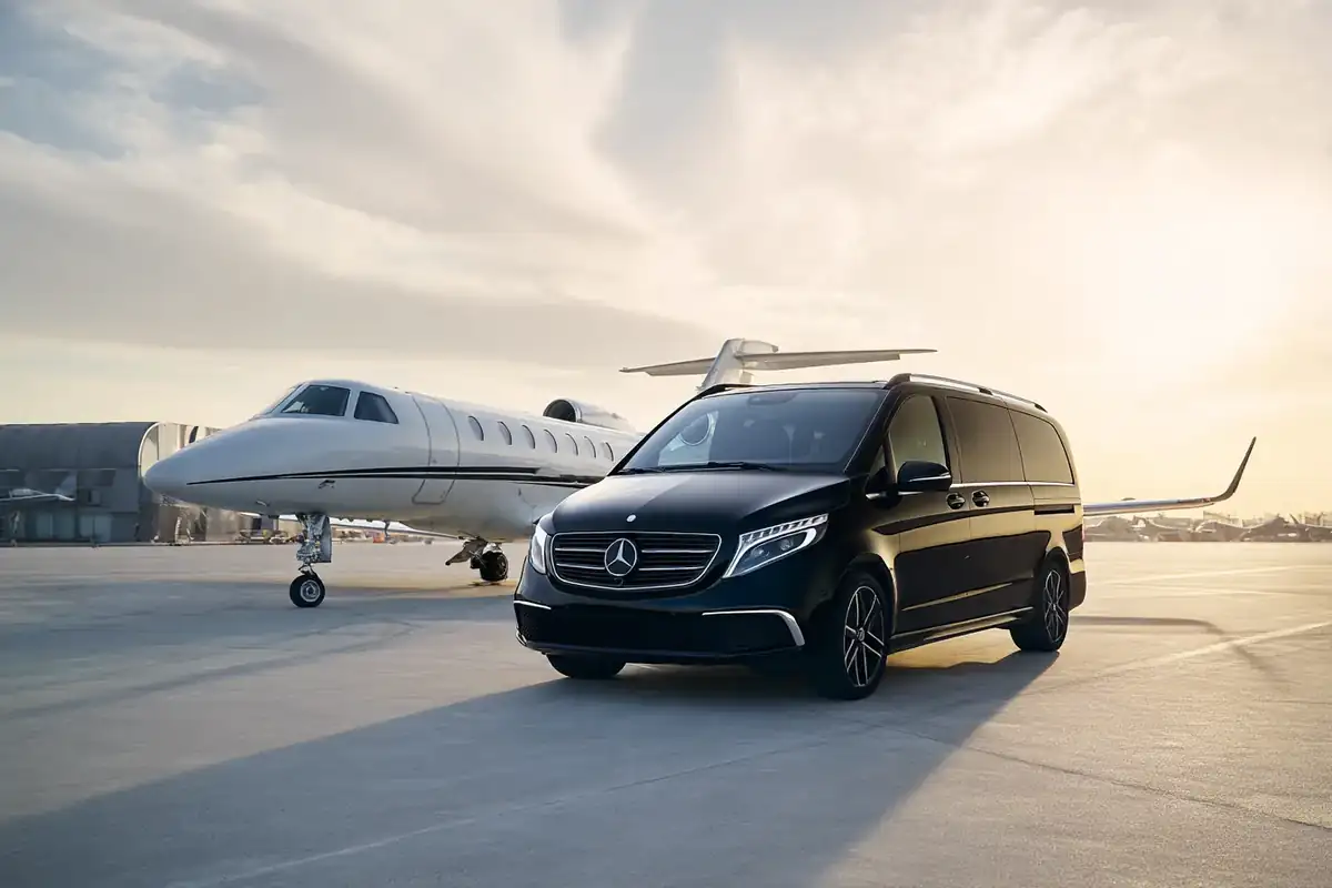 Black van leaving a private jet on a misty tarmac at dawn.